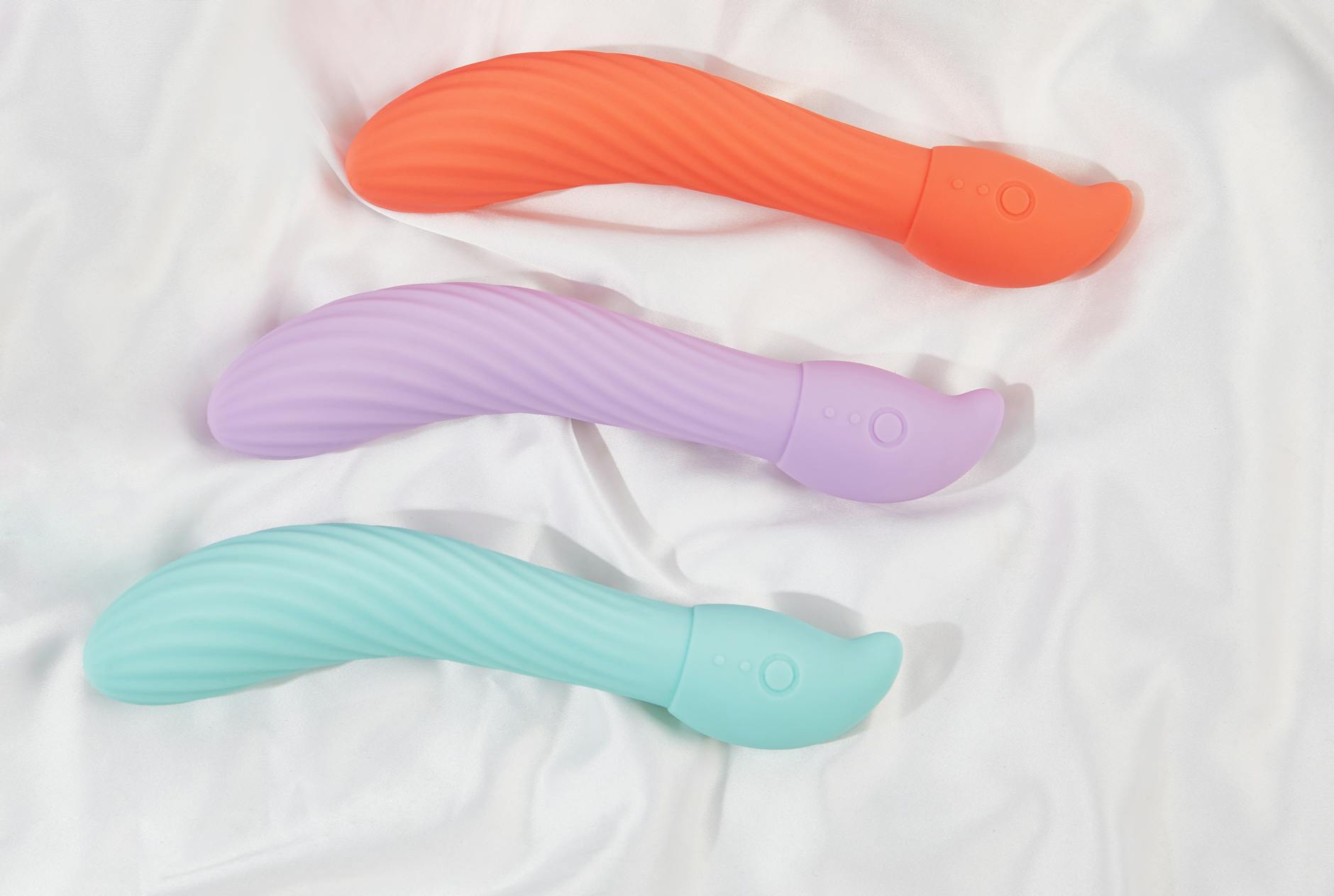 A stylish teal vibrator on smooth white silk fabric, symbolizing gentle sensory recovery