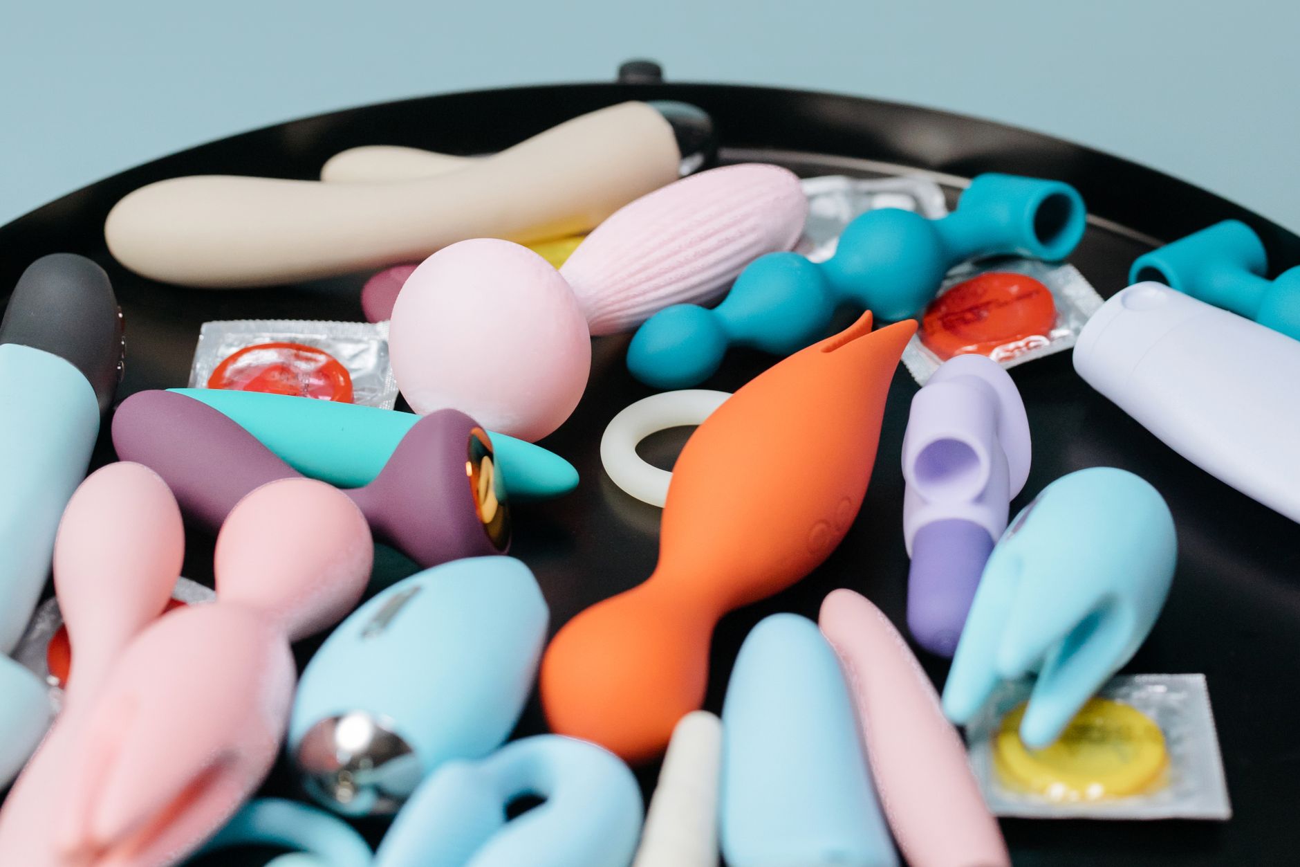 A collection of various clitoral vibrators and toys in different colors and styles on a black tray